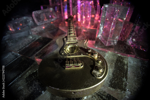 Music Concept: Guitar Miniature on a Dark Background with Vivid Light, Smoke, and Fire Effects. Golden electro guitar under a Dramatic Spotlight.