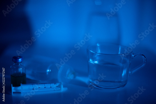 Laboratory mood captured. Scientific setup with neon hue. Test tube and glassware on shiny surface. Reflective laboratory environment with subtle liquid details and glowing tone