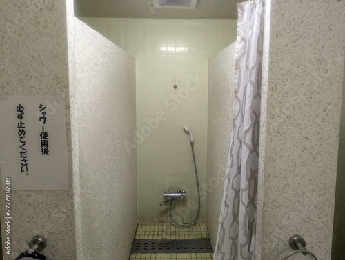 シャワーカーテンのある個室シャワーと止水の注意書き 屋内プールのシャワーブース