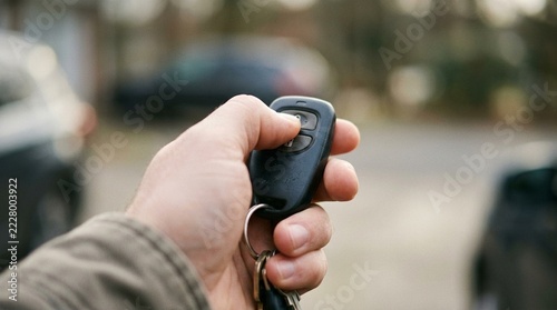 Close up of a hand pressing a button on a key fob token in soft focus, one-time password token and two-factor security