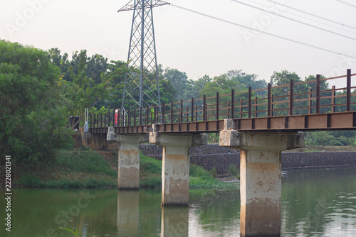 Fotografie Wide view of an iron girder bridge crossing over a tranquil river with concrete
