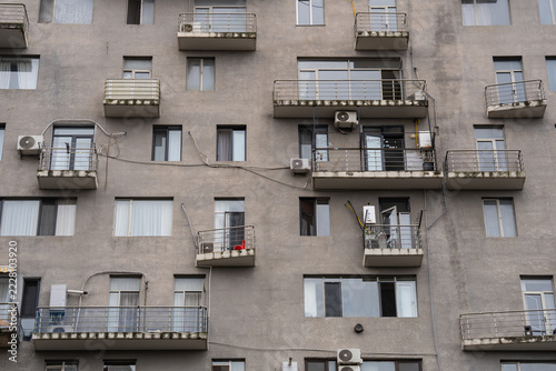 Weathered apartment building with messy air conditioners jutting out from walls in Batumi, Georgia, wiring hanging across residential house structure wall with haphazard balconies damaged by mold.