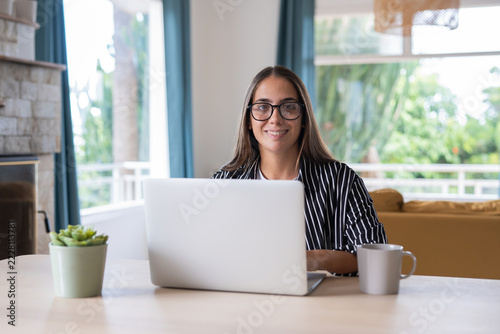 Fotografie Woman plans a trip on her laptop at home while smiling at the camera