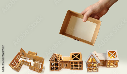 Blank cardboard box in hand with copy space. Christmas budget corporate template with gingerbread house as cozy festive home metaphor