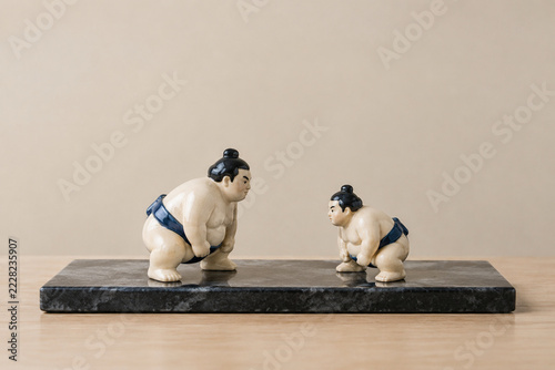 Two ceramic sumo wrestler figurines on dark stone tray, balance and friendly rivalry concept