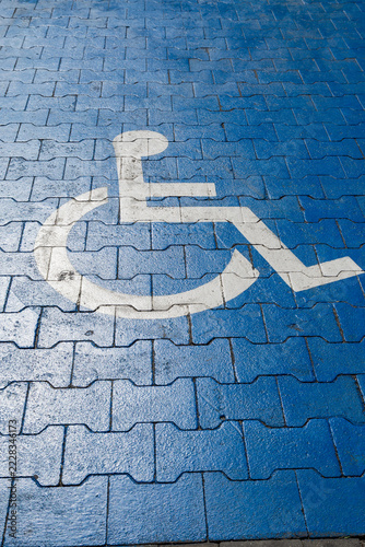 Obraz na plátně A white parking sign for people with mobility impairments on blue cobblestones