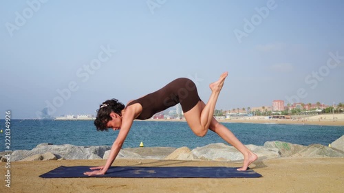 Woman practicing a vinyasa yoga flow on the beach