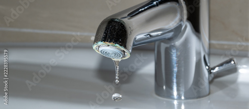 Verchromter Wasserhahn tropft über dem Waschbecken