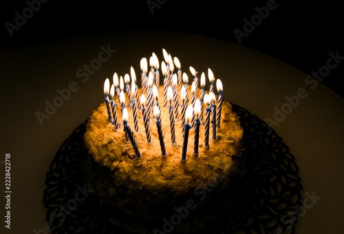 Obraz na plátně Birthday cake with lit candles burning brightly in dark room.