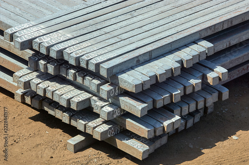 Close up of stacked raw steel billets with batch numbers stored in an industrial yard