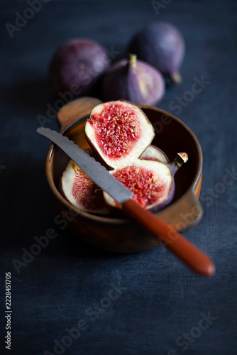 Ripe figs halved and whole in wooden bowl with knife