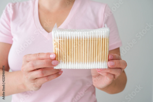 A woman holds a package of cotton swabs