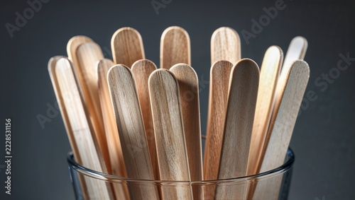 Wooden craft sticks standing upright in a clear glass