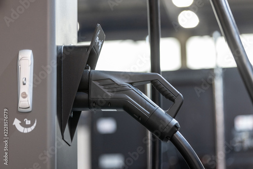 close-up of an electric vehicle charging plug in a charger station socket.
