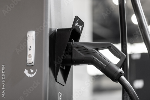 close-up of an electric vehicle charging plug in a charger station socket.