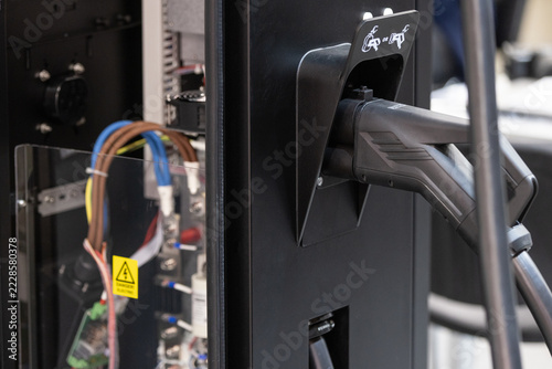 close-up of an electric vehicle charging plug in a charger station socket.