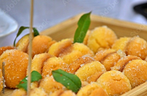 Sugar-coated peach cookies decorated with green leaves in tray