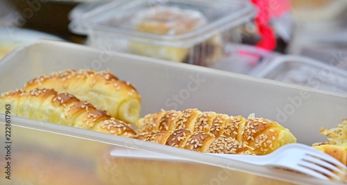 Golden pastry rolls with sesame seeds rest inside a container