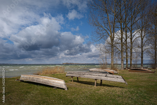 Old rural wooden, fishing boats is moored on the shore of a lake. A windy day
