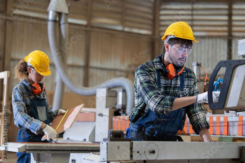Worker measures wood in a warehouse during the day while wearing safety gear