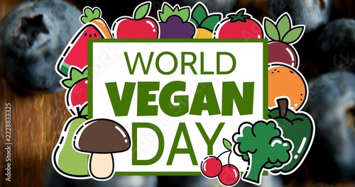 Showing WORLD VEGAN DAY sign over blurred blueberries on plank, white-outline stickers