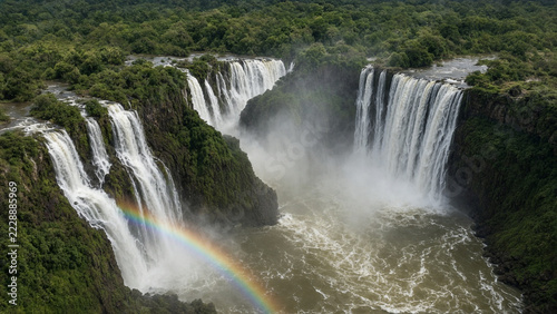 Large waterfalls plunging into a misty gorge with a rainbow in lush subtropical rainforest, Argentina