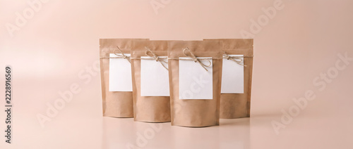 Kraft paper tea packaging mock up with blank labels on pastel studio background