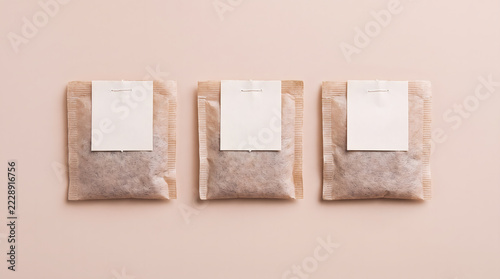 Three blank tea sachet packages arranged on a soft pink background