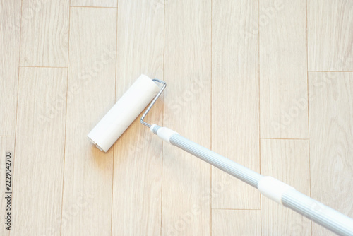 Cleaning white laminate flooring using an adhesive cleaning roller close-up, top view.