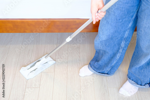 Woman cleaning floors with mop, side view.