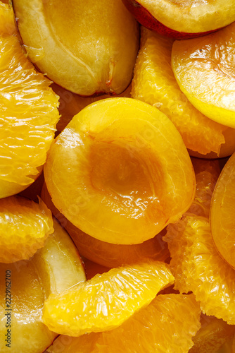 Fresh halved yellow plums with peeled orange segments, juicy fruit background close-up
