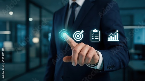 Professional in suit pressing glowing holographic button on digital interface with target checklist and growth chart icons representing business strategy and workflow management