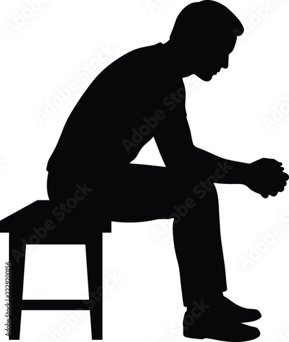 Obraz na plátně Man sitting on stool silhouette profile view with head bowed down in deep though