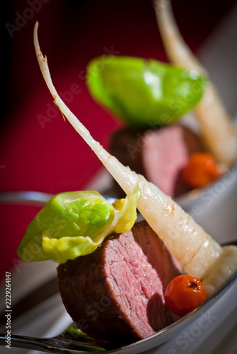 Aperitif spoon featuring an artfully arranged gourmet amuse-bouche: pan-seared beef tenderloin (served medium-rare) with Savoy cabbage and parsnip purée.