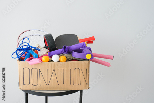 Donation box with sports equipment on a gray background