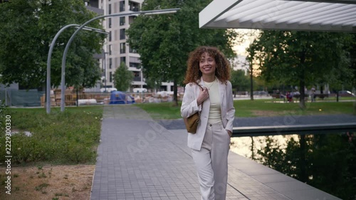 Businesswoman answering smartphone while walking in modern city park