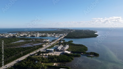 Aerial view of the Florida Keys with a highway bridge connecting islands, surrounded by turquoise waters, coastal mangroves, and scattered buildings in Florida, United States.