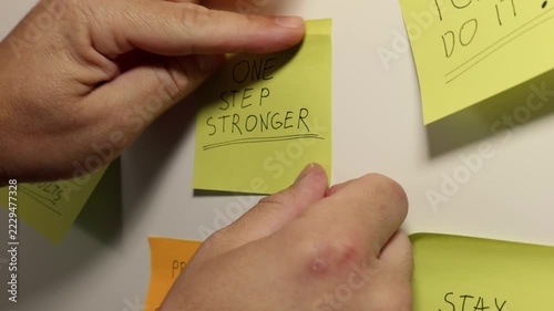 ONE STEP STRONGER on a Yellow Sticky Note Among Motivational Messages