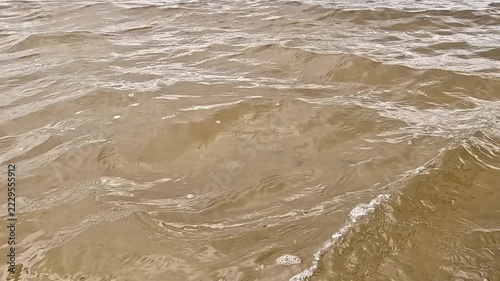 Clear water flows evenly across the frame, with small waves and ripples constantly forming on the surface as the current moves forward under natural daylight outdoors.