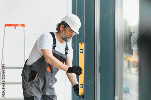 Professional worker installing window glass leveling building home