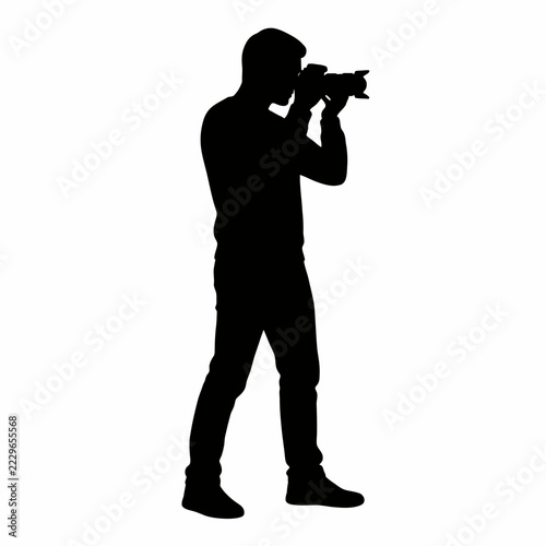 Black silhouette of a professional male photographer standing and holding a digital camera to take a picture isolated on white background