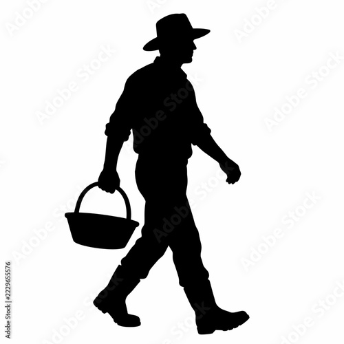 Silhouette of a Rural Farmer Wearing a Hat and Carrying a Basket While Walking in the Countryside