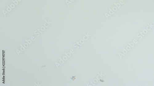 Star shaped confetti falling through the air against light background. Party celebration and festive background