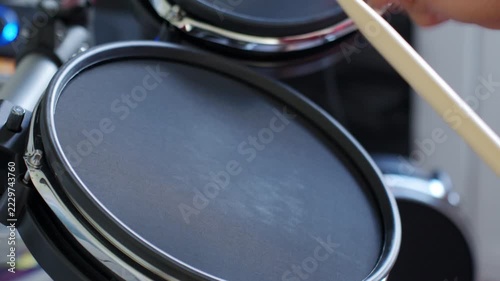 Drummer playing electronic drums with wooden drumsticks. Hands hitting black mesh drum pad during drumming. Music practice