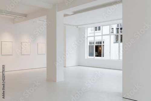 Minimalist art gallery interior with white walls and large windows showcasing minimalist line art on display