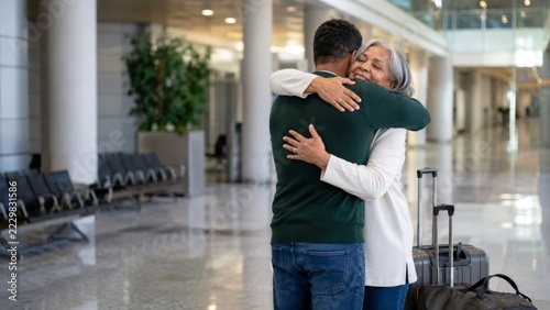 Family farewell hug with luggage in airport terminal