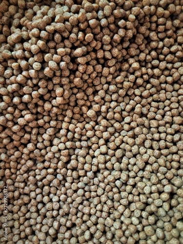 Dense mass of floating fish feed pellets texture background for catfish aquaculture and animal nutrition.