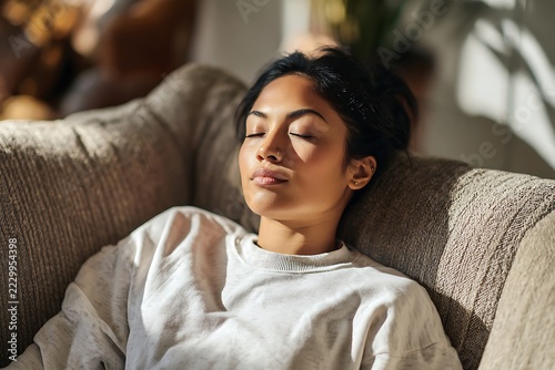 relaxed woman resting on sofa at home with eyes closed. mental wellness, stress relief and self care lifestyle concept