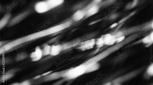 Monochrome abstract light streaks with grainy film texture and diagonal motion blur creating a dark moody atmosphere for artistic backgrounds and minimalist graphic design projects in black white