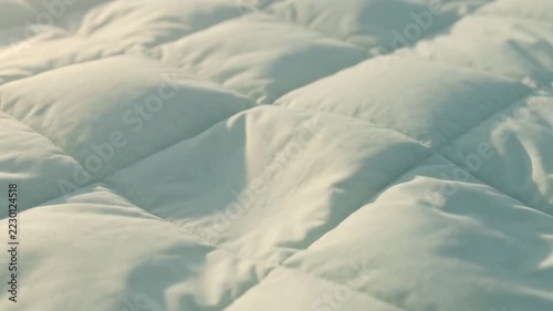 Soft and plush quilted duvet texture, closeup of white bedding fabric with soft morning light
